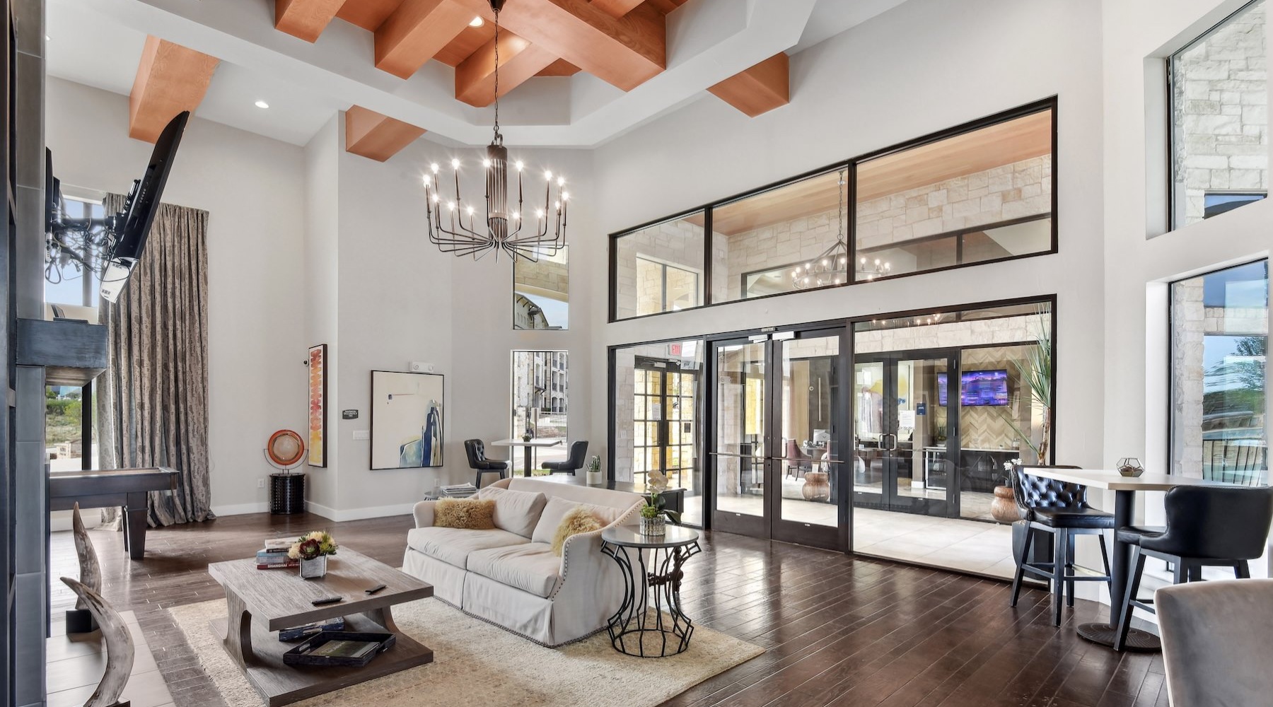 a spacious lounge with tall ceilings and wood floors