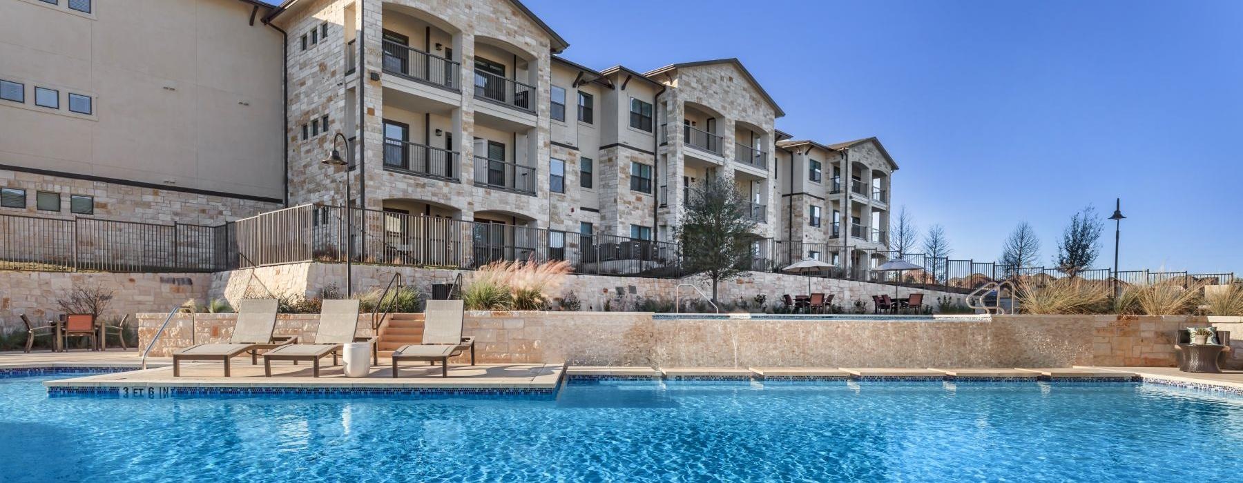 a pool with chairs and a building in the background